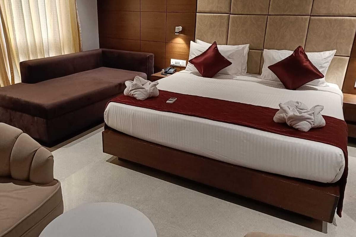 Quarto de hotel moderno com uma cama grande, um sofá e uma cadeira.