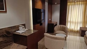 A modern hotel room with a flat-screen TV, a coffee station, a sofa, and a dining area. - Hotel Darwin City  (Port Blair)