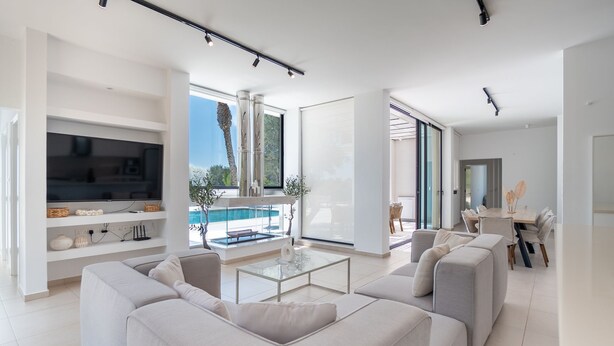 Ein modernes Wohnzimmer mit Pool, weißen Möbeln und Essbereich.
