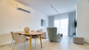 Un salon moderne avec une table ronde, deux fauteuils, un canapé et un téléviseur.