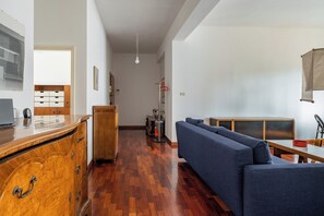 Una sala moderna con un aparador de madera, un sofá azul y un comedor con mesa y sillas.