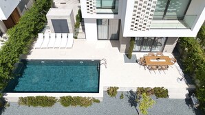 Een modern woongebouw met een zwembad, buitenzitplaatsen en een verzorgde tuin.