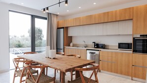 Een moderne keuken met houten kastjes, een eettafel met stoelen en een vaatwasser.