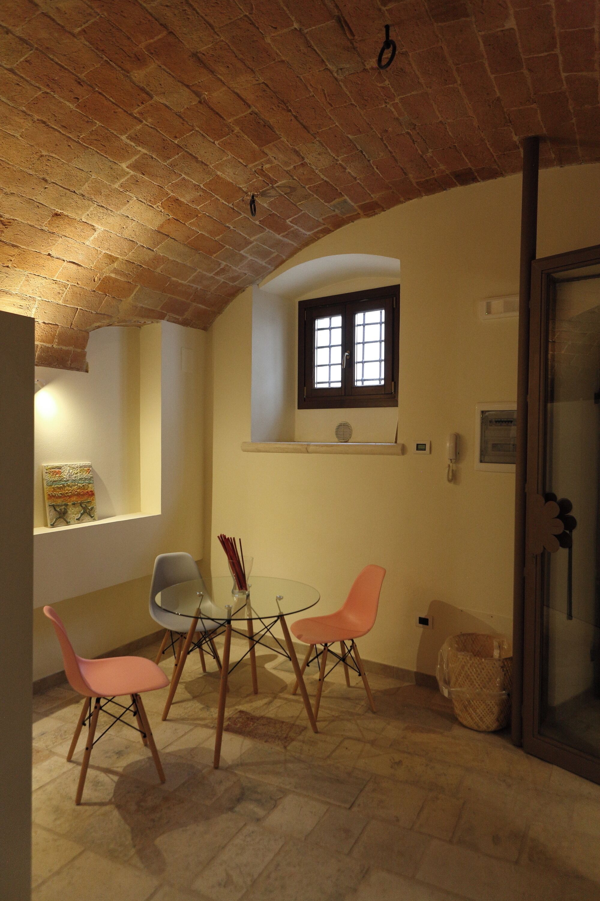 A dining area with a brick ceiling, a window with blinds, and a table with chairs.