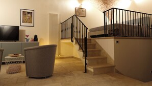 A living room with a staircase, a television, and a framed picture on the wall.