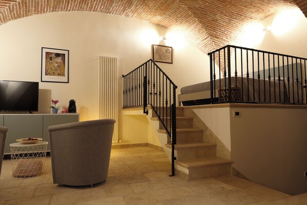 A living room with a staircase, a television, and a framed picture on the wall.