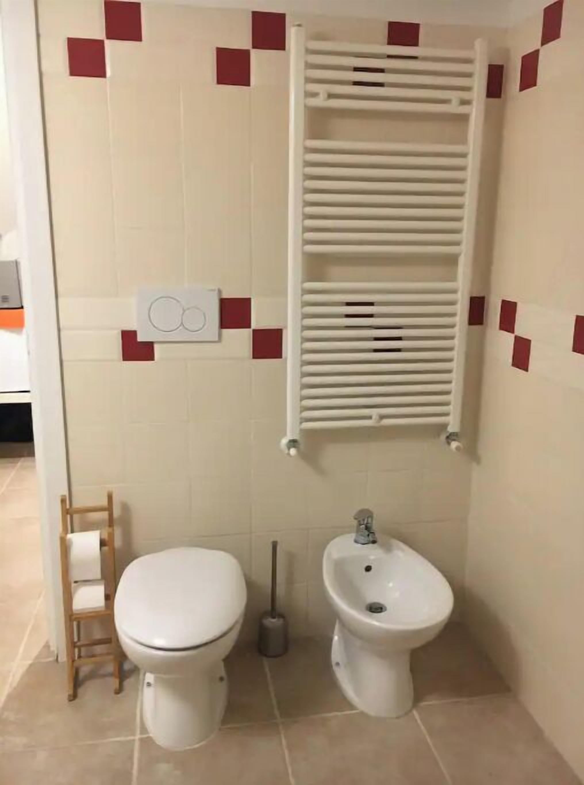 A small bathroom with a toilet, bidet, and a towel rack.