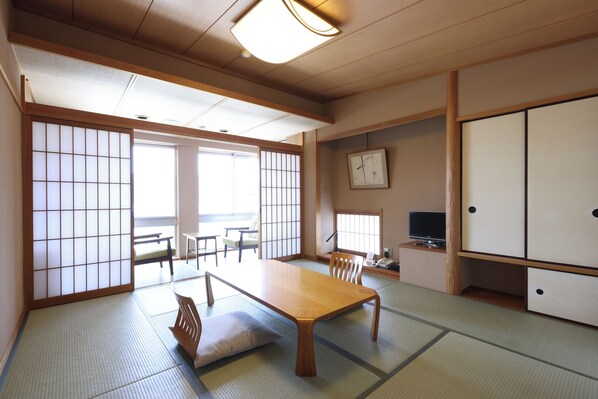 Um quarto japonês tradicional com tatames, uma mesa de madeira baixa e portas deslizantes.