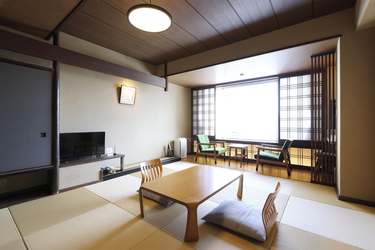 Una habitación japonesa tradicional con suelo de tatami, una mesa baja y puertas correderas.