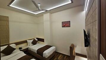 A hotel room with two beds, a ceiling fan, a small table, and a wall-mounted TV.
