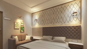 A modern bedroom with a large bed, a sofa, and a decorative wall panel. - Shree Shivya Namahstubhyam Hotel (Varanasi)