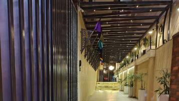 A corridor with a tiled floor, metal railings, and potted plants.