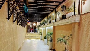 A corridor with tiled flooring, decorative metal railings, and potted plants. - Shree Shivya Namahstubhyam Hotel (Varanasi)