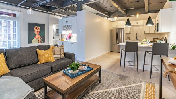 A modern living room with a sofa, coffee table, and kitchen area with bar stools. - Gorgeous Villa Steps to La Jolla Cove (San Diego)