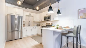 A modern kitchen with white cabinets, stainless steel appliances, a central island, and pendant lighting. - Gorgeous Villa Steps to La Jolla Cove (San Diego)