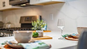 A kitchen counter with a bowl, a glass, a potted plant, and a cutting board. - Gorgeous Villa Steps to La Jolla Cove (San Diego)