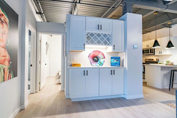 A modern kitchen with white cabinets, a central island, and pendant lighting.