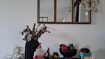 A room with a black table displaying various decorative items including a Santa Claus figurine, a vase with dried branches, and a bowl with ornaments.