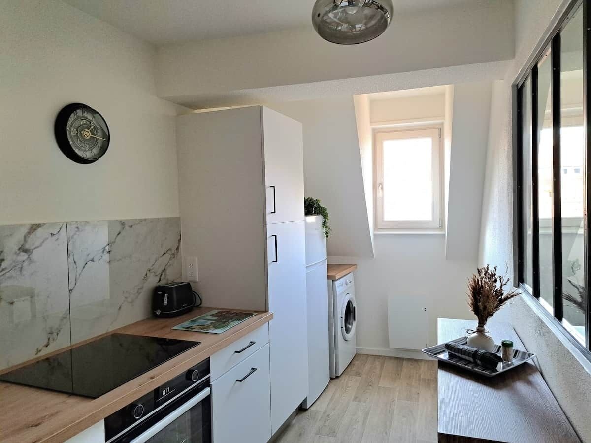Eine kompakte Küche mit Einbauofen, Waschmaschine und einem Fenster für natürliches Licht.