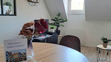 A modern interior with a round table, a bonsai tree, and a welcome sign.