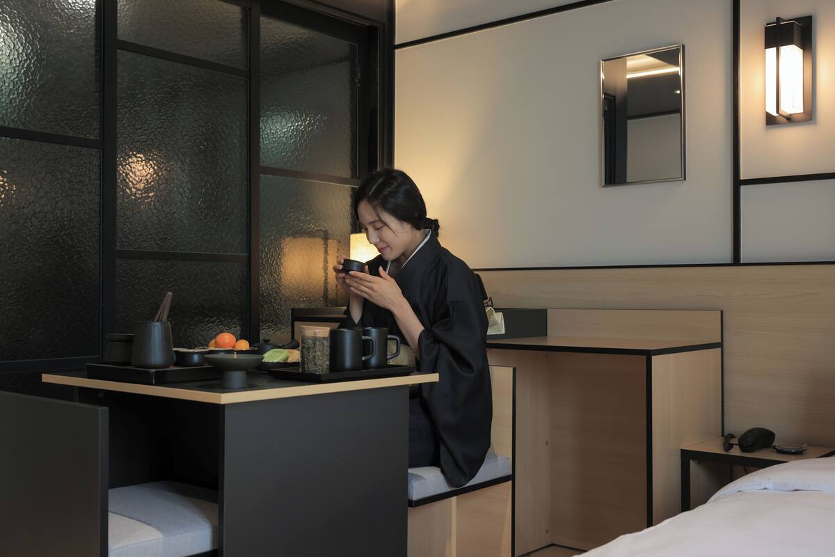 Et moderne hotelværelse med et lille tekøkken, en seng og et siddeområde med udsigt over byen.