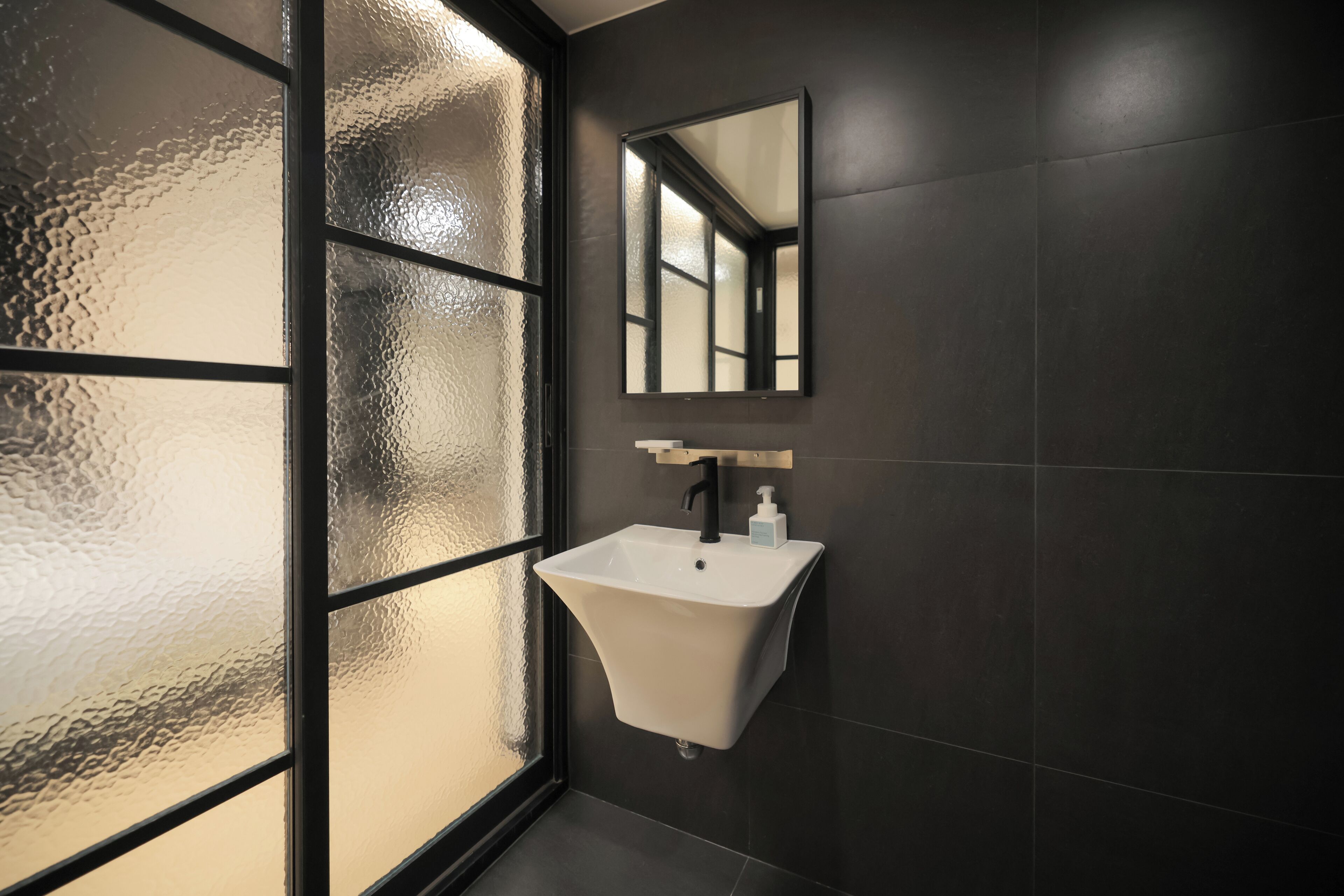 A bathroom with a white sink, a mirror, and a frosted glass window.