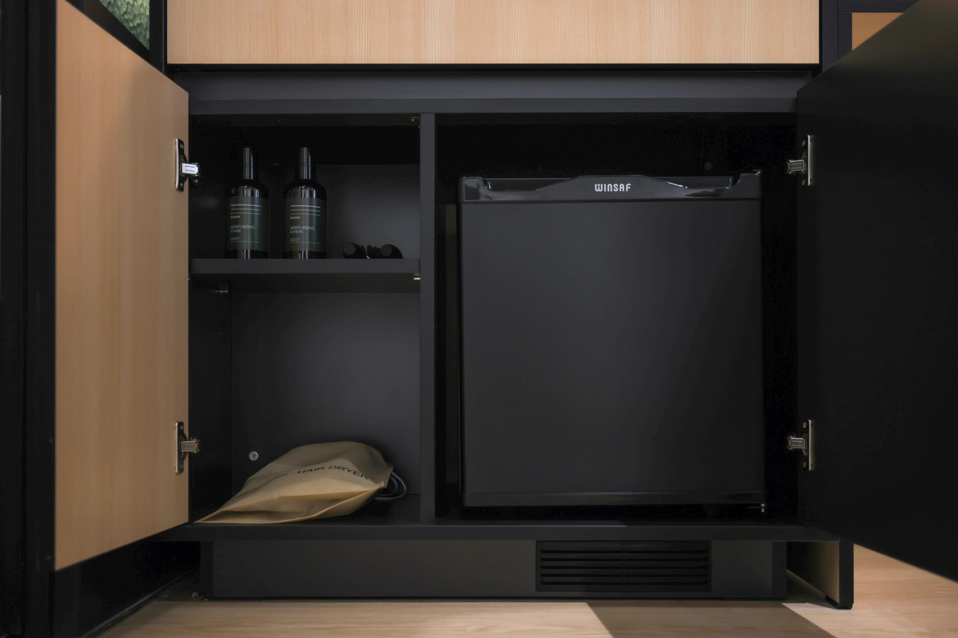 A compact, modern wardrobe with a built-in mini-fridge and shelving for storage.