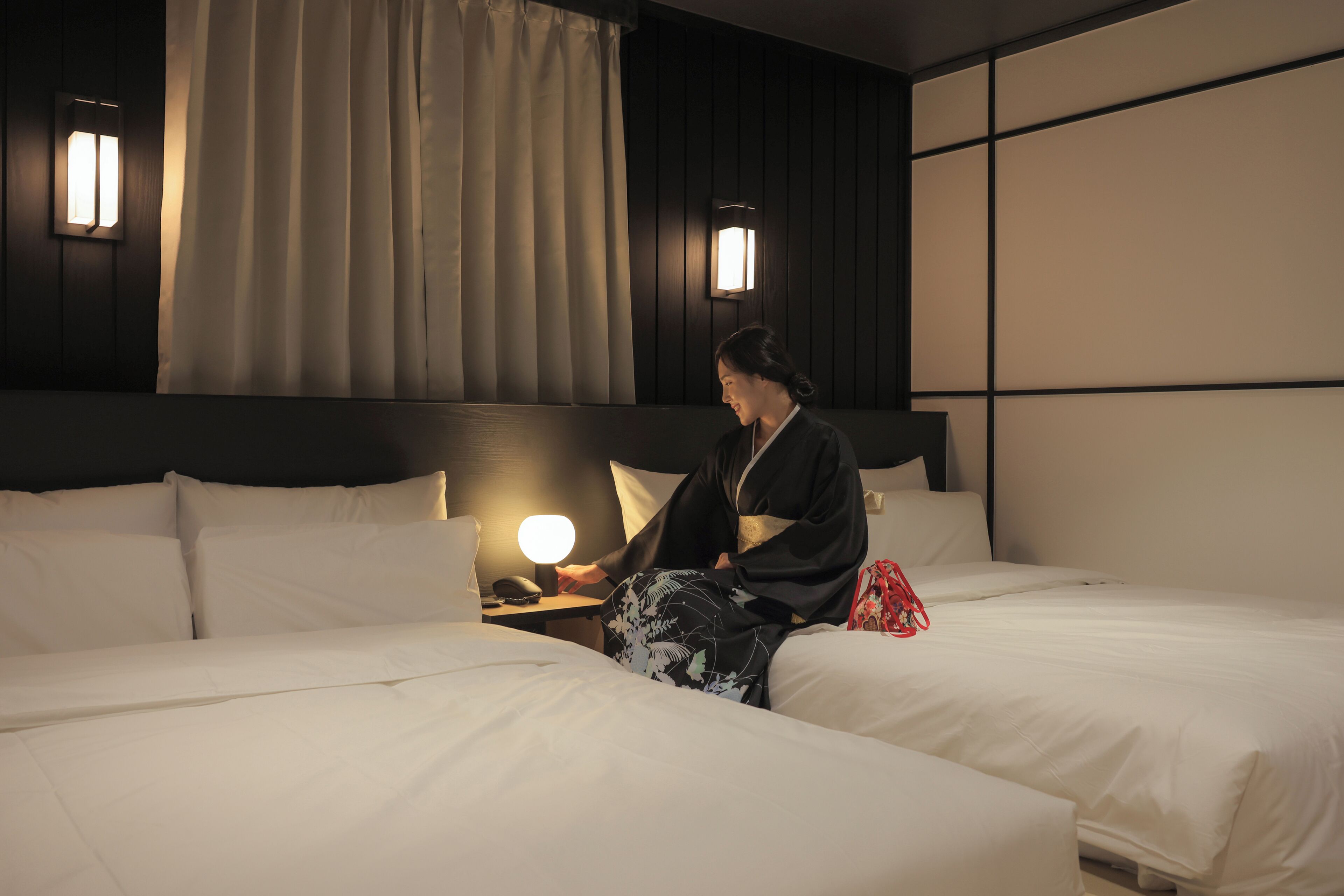 Habitación de hotel con cama, mesita de noche, lámpara e iluminación en la pared.