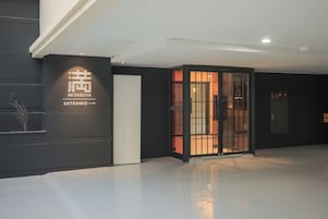 Una entrada moderna con un letrero que dice "MITSUYA ENTRANCE" y una puerta japonesa tradicional.