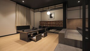 A modern living room with a wooden floor, a central seating area with cushions, a low table, and a wall-mounted shelf with framed pictures. - Mitasuya Ryokan Hotel Gumi Wonpyeong Branch (Gumi)