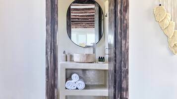 A bathroom with a round mirror, a sink, and a towel rack.
