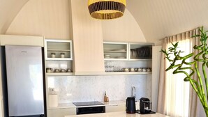 A modern kitchen with a built-in refrigerator, a dining area with wicker chairs, and a large island.