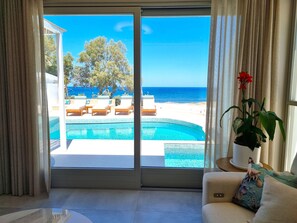 A room with a view of a swimming pool, lounge chairs, and a beach. - Nerea Seaside VIlla on the Beach (Monolithos)