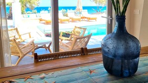 A large window with a view of a pool and lounge chairs.