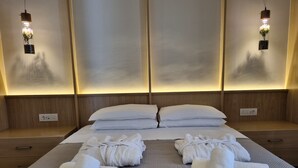 A hotel room with a large bed, two bedside tables, and a wall-mounted light fixture.