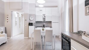 Eine moderne Küche mit weißen Schränken, einem Esstisch mit Stühlen und einem eingebauten Backofen.