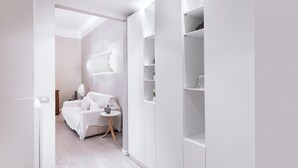 Ein modernes, minimalistisches Schlafzimmer mit einem weißen Bett, Nachttisch und Einbauschränken.