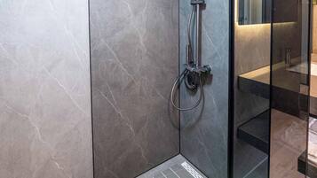 Un baño moderno con cabina de ducha de vidrio, tragaluz y suelo de mármol.