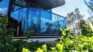 A modern building with large glass windows, a curved roof, and surrounded by greenery. - Mesopotam Agrotourism Resort (Mesopotam)