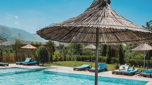 A swimming pool with lounge chairs and umbrellas. - Mesopotam Agrotourism Resort (Mesopotam)