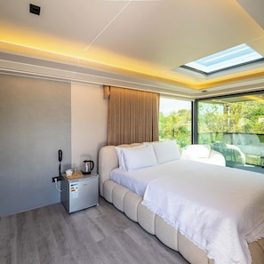 A modern hotel room with a large bed, a coffee maker, and a view of greenery. - Mesopotam Agrotourism Resort (Mesopotam)