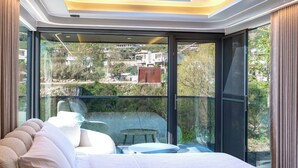 A bedroom with a skylight, large windows, a bed, and a view of the outside. - Mesopotam Agrotourism Resort (Mesopotam)
