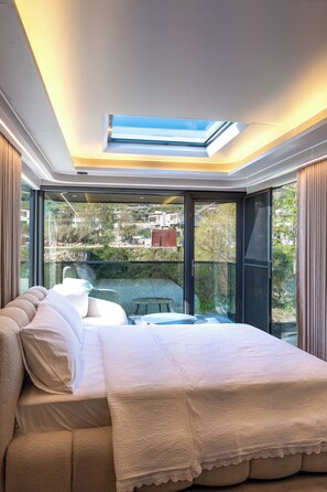 Un dormitorio con tragaluces, ventanas amplias, una cama y vistas al exterior.