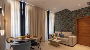 Una sala de estar moderna con comedor, un sofá y una pared con diseño.