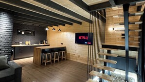 Une cuisine moderne avec un plan de travail en bois, des tabourets de bar et un mur d’accent en briques noires.