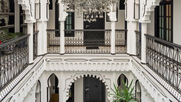 A multi-level courtyard with ornate white architecture, a chandelier, and a potted plant.