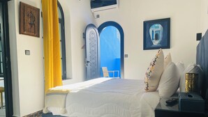 A bedroom with a bed, a nightstand, a lamp, and a window with curtains.