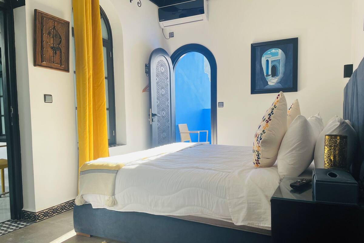 A bedroom with a bed, a nightstand, a lamp, and a window with curtains.