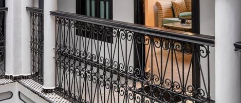 Un edificio blanco con ventanas de marco negro y un balcón con barandillas de metal negras y ornamentadas.