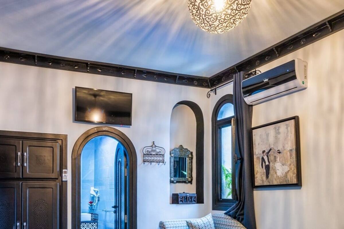 A cozy room with a patterned ceiling light, a sofa, a small table, and a view into a bathroom.